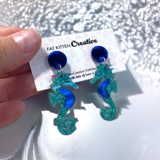 Seahorse dangle. Teal Holographic glitter, blue mirror acrylic on blue mirror topper.